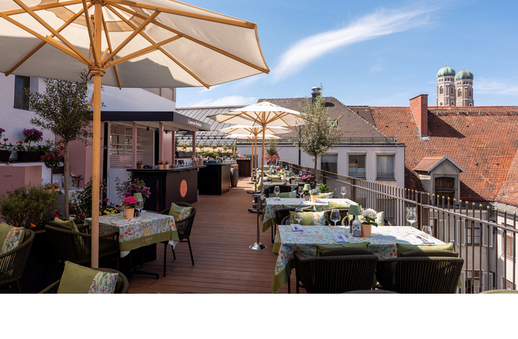 Die Dachterrasse mit Sonnenschirmen, vielen bunten Sitzgruppen und Blick auf die Frauenkirche.