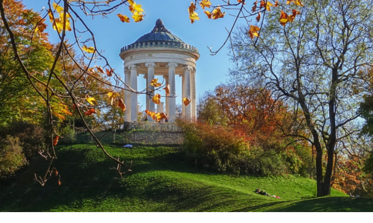 Rundtempel im Englischen Garten München, umgeben von herbstlichen Bäumen und grünem Hügel.
