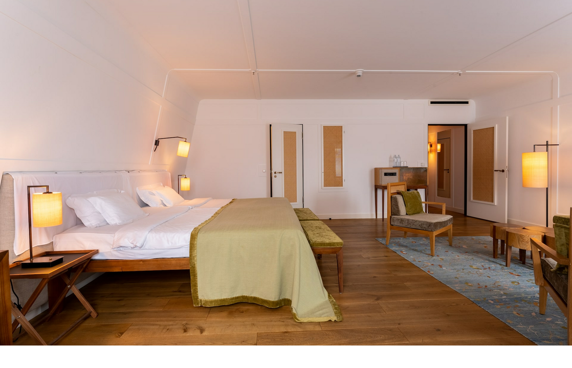 Suite at the LOUIS Hotel Munich Bright, modern hotel room with large bed, wooden floor, stylish lamps and seating area in the LOUIS Hotel Munich.