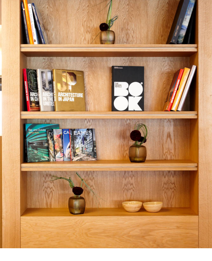 Holzregal im LOUIS Hotel mit Architektur-Büchern, Vasen und Dekoschalen.