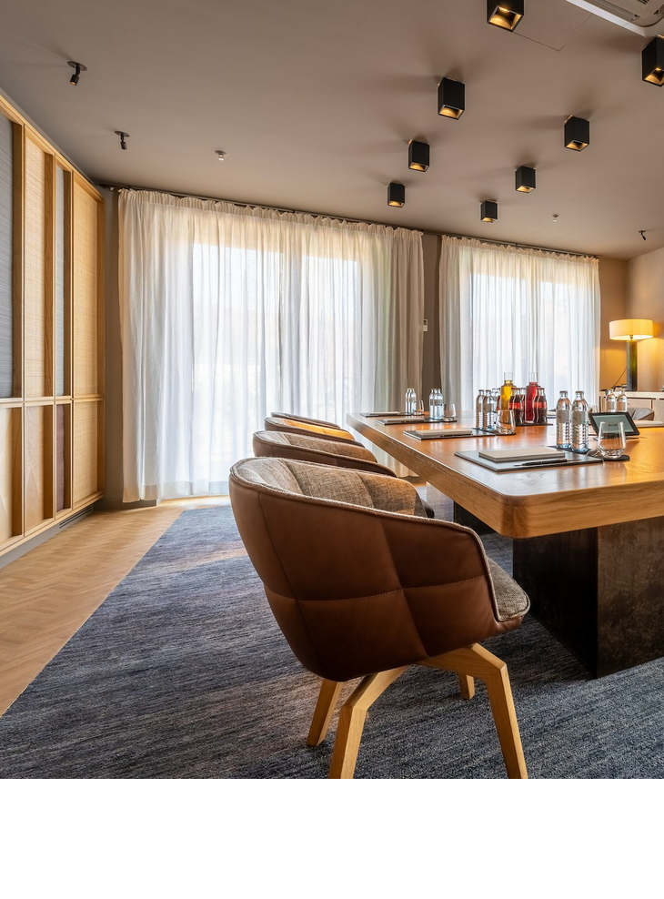Boardroom l LOUIS Hotel Munich Modern conference room in the LOUIS Hotel Munich with a large wooden table, stylish chairs and natural light.