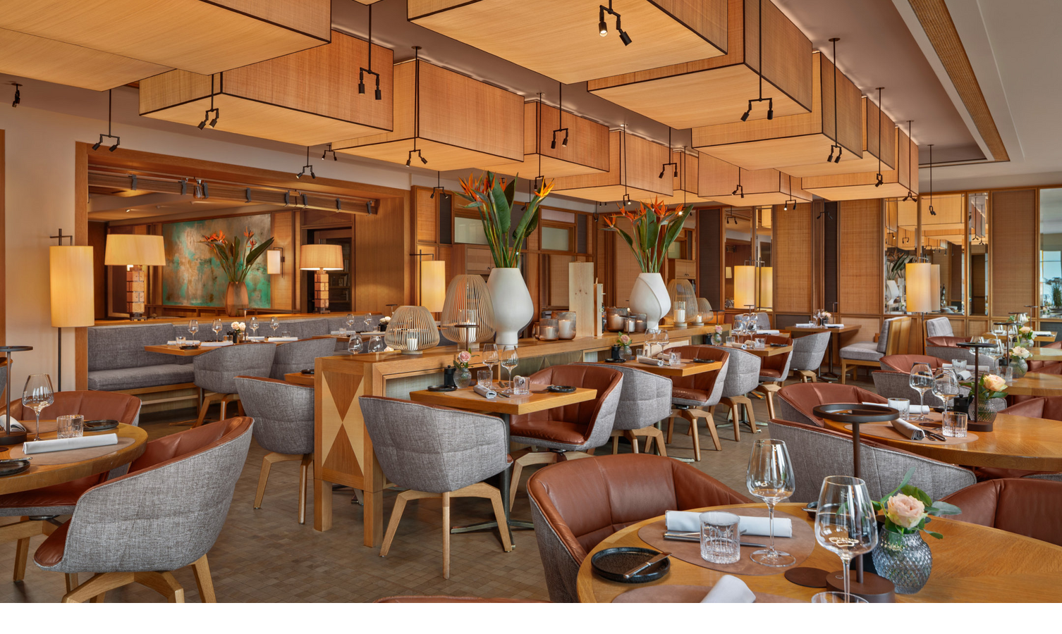 Elegant restaurant in the LOUIS Hotel Munich with stylish wooden tables, cozy armchairs and a warm lighting ambience.