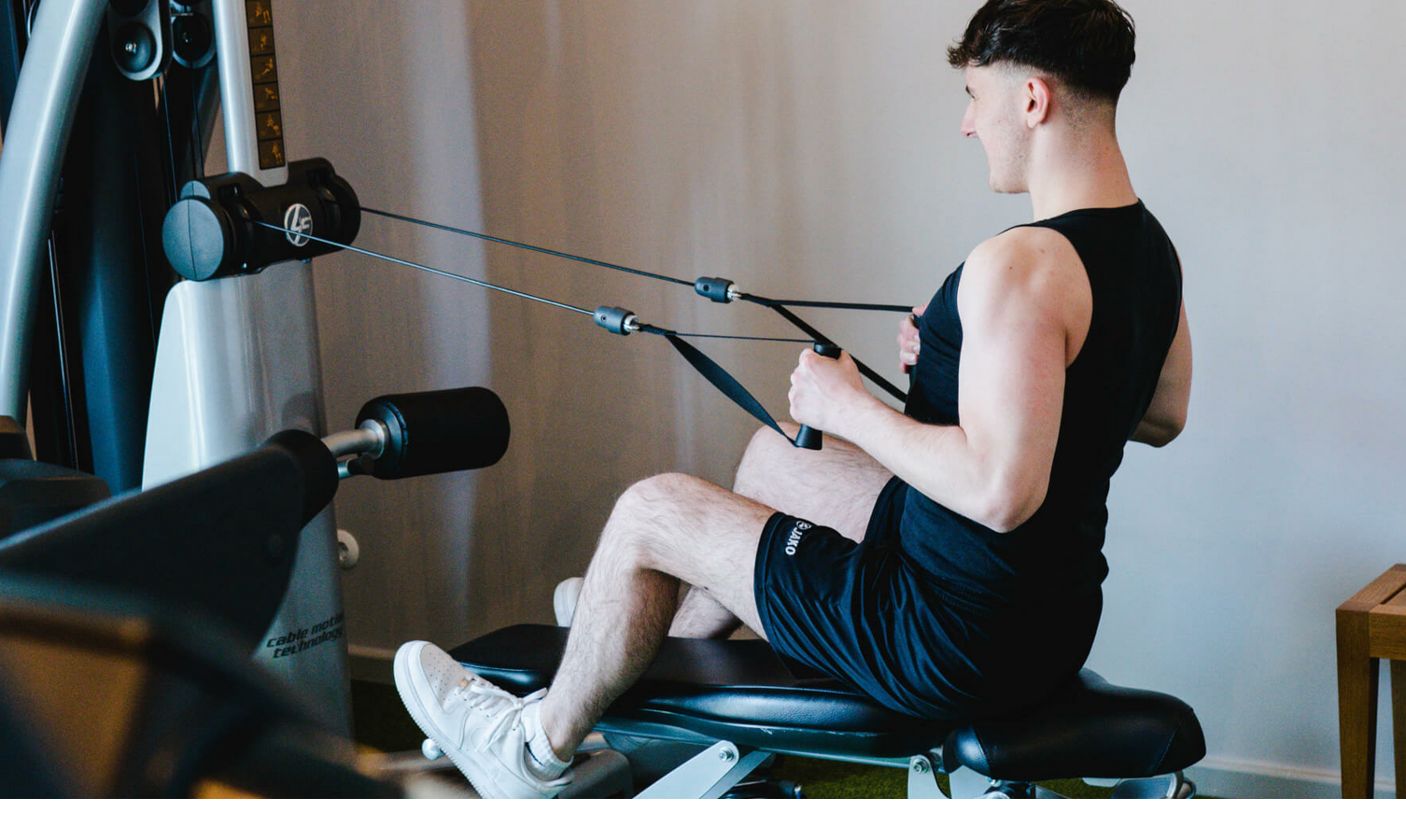 Person trains on fitness equipment at the LOUIS Hotel Munich. Modern fitness room with strength training facilities.