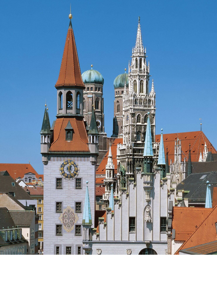 Vier Münchner Türme am Marienplatz Blick auf Münchens Altstadt mit historischen Türmen und roten Dächern vor klarem, blauem Himmel.