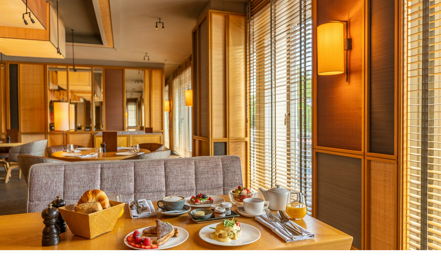 Gemütliches Hotelrestaurant mit gedecktem Frühstückstisch, Holzmöbeln und warmem Licht.
