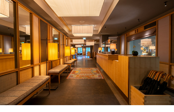 lobby with reception at the LOUIS Hotel München Elegant hotel lobby with wooden walls, warm lighting, benches and carpet at the LOUIS Hotel Munich.