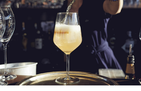 Aperitif on The LOUIS Roof Terrace A sparkling drink is poured into a wine glass on a tray at the LOUIS Hotel Munich.